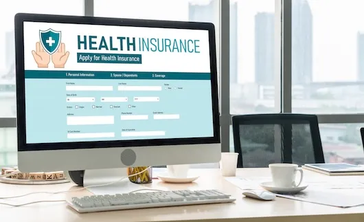 Computerbildschirm mit geöffneter Website zur Anmeldung für eine Krankenversicherung – Formular mit Eingabefeldern zu persönlichen Daten